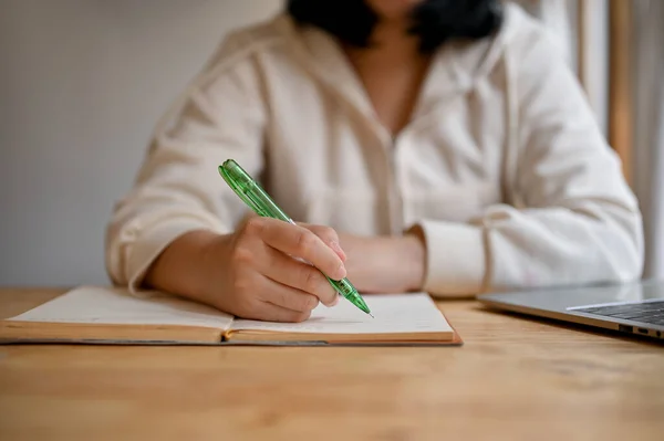 白いパーカーを着た若いアジア系女子大生が本に何かを書いている姿をクローズアップし 喫茶店でリモートワーク — ストック写真