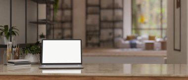 Çalışma alanı, laptopun beyaz ekran modellemesi, resim araçları, kitap, dekor fabrikası ve modern bir oturma odasının bulanık arkaplanının üzerindeki bir masanın üzerine kopyalama alanı. 3d görüntüleme, 3d illüstrasyon