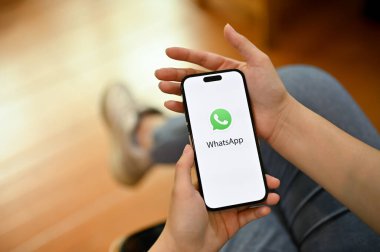 Chiang Mai, Tayland - 18 Nisan 2023: Telefonunda WhatsApp uygulaması kullanan bir kadın. Ekranda WhatsApp logosu olan iPhone. 