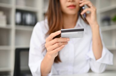 Genç bir Asyalı kadının yakın plan görüntüsü kredi kartı çağrı merkeziyle iletişime geçerek onları sorunlar hakkında bilgilendirir veya bazı sorular sorar..