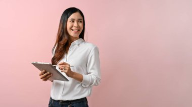 Pembe izole edilmiş arka planda dururken dijital tablet tutan genç Asyalı kadın görüntüsü.
