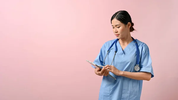 Νεαρή Όμορφη Γυναίκα Γιατρός Γράφει Στο Tablet Ενώ Στέκεται Ροζ — Φωτογραφία Αρχείου