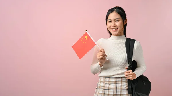 Asian girl showing a China flag on pink isolated background, education concept. study abroad concept.