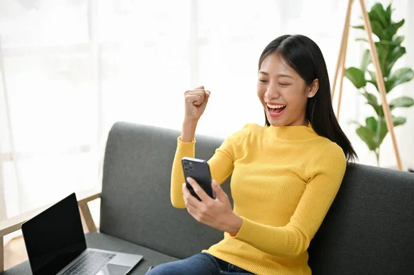 stock image Overjoyed pretty Asian woman celebrating after receiving a good news from her phone.