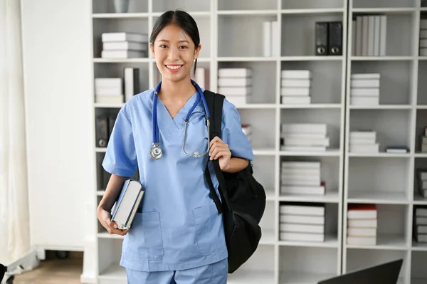 Portrait of young Asian medical student smiling and standing in the study room with stethoscope on her shoulder.