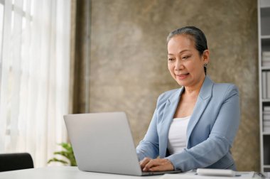 Başarılı ve profesyonel iş kadını dizüstü bilgisayarını kullanıyor, bilgisayarında iş projesi üzerinde çalışıyor..