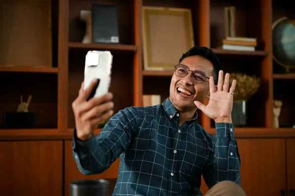 一个快乐的千年亚洲男人和他的朋友在客厅里放松的时候打了电话 人与技术概念 — 图库照片
