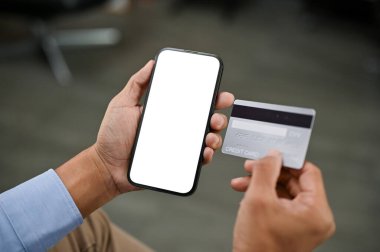 Asyalı bir adamın cep telefonu bankacılığı uygulamasını bir odada otururken kullanırken yakın plan görüntüsü. Akıllı telefon beyaz ekran modeli. Çevrimiçi ödeme, online alışveriş, Nakitsiz