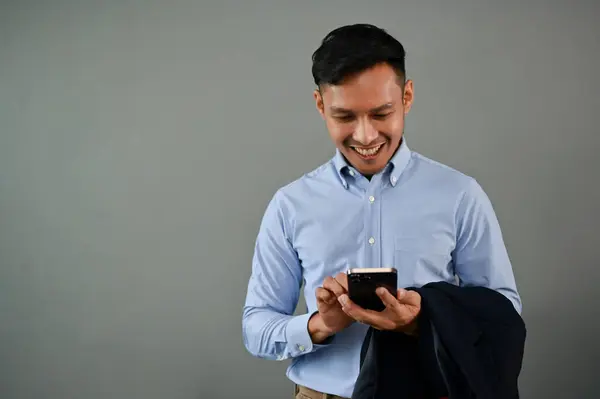 快乐千年亚洲商人使用他的智能手机 同时站在一个孤立的灰色背景 Chat Text Message Sms Email Social Media — 图库照片