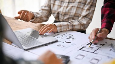 Profesyonel mühendislerden oluşan bir ekibin yakın plan görüntüsü, bir mühendis ofisinde birlikte çalışarak, bir yapı planını tartışmak ve planlamak için toplandı..