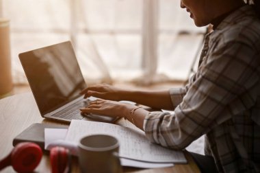 Asyalı bir kadının dizüstü bilgisayarını kullanırken ve oturma odasındaki kahve masasında çalışırken yakın plan görüntüsü..