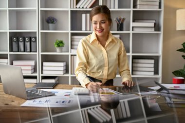 Güzel bir Asyalı iş kadını yeni bir proje için yeni bir iş planı hazırlıyor, bilgisayar ekranına bakıyor ve ofiste çalışıyor..