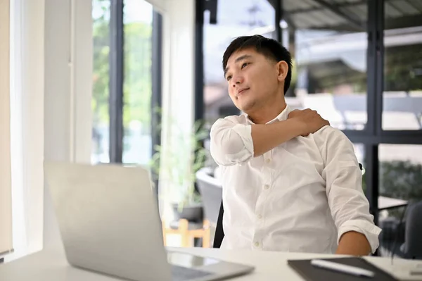 Tired Overworked Millennial Asian Businessman Rubbing His Shoulder While Sitting — Stock Photo, Image