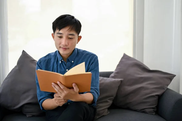 Focalisé Heureux Homme Asiatique Millénaire Lecture Livre Sur Canapé Dans — Photo