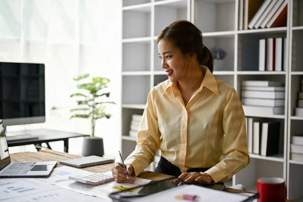 stock image Professional millennial Asian female accountant working in her office, planning business financial investment plan, reviewing accounting sales reports.