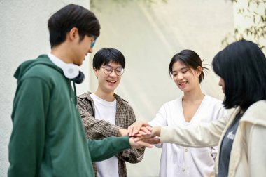 Bir grup neşeli Asyalı üniversite öğrencisinin bir araya gelip takım çalışması ve birlik göstermesi..