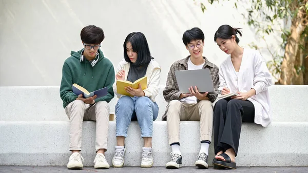 图片中的亚洲大学生坐在校园休闲区的长椅上 讨论工作 使用笔记本电脑 以及辅导数学 大学生活方式概念 — 图库照片