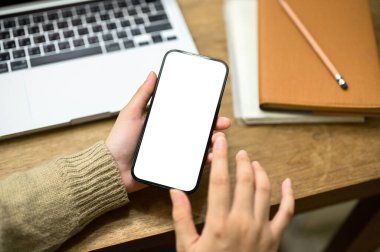 İş yerinde akıllı telefonunu kullanan rahat kazaklı bir kadının yakın plan fotoğrafı. cep telefonu beyaz ekran modeli