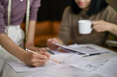 Yeni tasarımlarını çizen ve stüdyoda birlikte çalışan iki profesyonel kadın moda tasarımcısının yakın plan görüntüsü..
