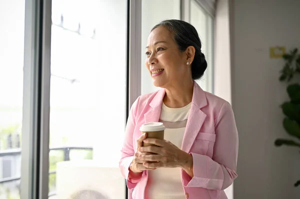 Atraktivní Okouzlující Starší Asijská Podnikatelka Stojí Okna Kávou Rukou Dívá — Stock fotografie