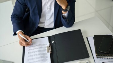 Resmi takım elbiseli profesyonel bir işadamının masasındaki kontratı imzalarken yakın plan fotoğrafı..