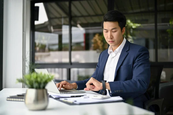 직업적 밀레니엄 아시아 사업가는 사무실에서 책상에서 일하는 시계에 시간을 합니다 — 스톡 사진