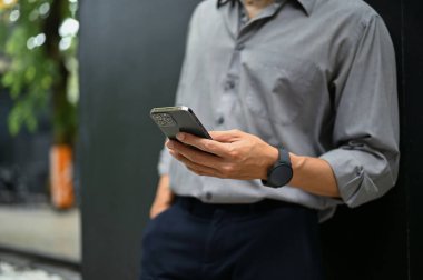 Bir iş adamının akıllı telefonunu kullanarak binanın dışında dikilirken mesajlarını ve e-postalarını kontrol ettiği görüntüler..