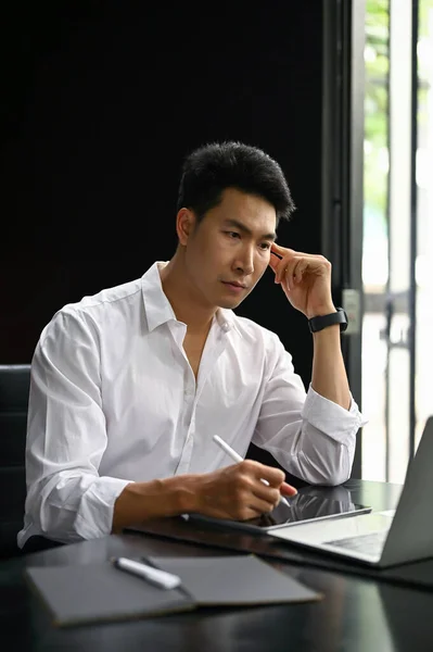 생각깊고 직업적 밀레니엄 아시아 사업가가 노트북 컴퓨터를 사용하여 자신의 프로젝트를 — 스톡 사진