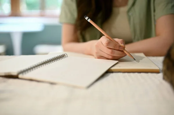 家で宿題をして紙に何か書いて鉛筆を持って日記を書いている若いアジアの女の子のクローズアップイメージ — ストック写真