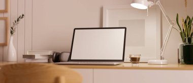 Laptop beyaz ekran maketi, masa lambası, kahve fincanı, kulaklık ve dekorlu minimum çalışma alanı. Görüntüyü yaklaştır. 3d görüntüleme, 3d illüstrasyon