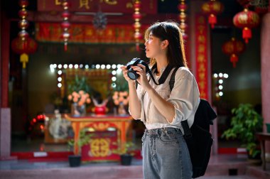 Kamerası ve sırt çantasıyla güzel ve mutlu bir Asyalı bayan turist güzel bir Çin tapınağını tek başına ziyaret etmekten hoşlanıyor. Tek başına seyahat kavramı