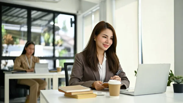 매혹적 밀레니엄 아시아 사무직 근로자 사무실에 그녀의 책상에서 노트북 컴퓨터로 — 스톡 사진