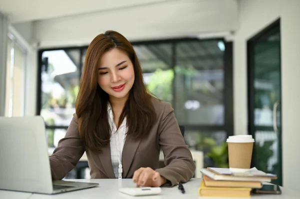 計算機を使用して美しい若いアジアの女性会計士と彼女のオフィスで彼女の机で彼女のアカウントの販売レポートに取り組んで — ストック写真