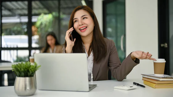 明るく魅力的な千年のアジアのビジネスマンや女性のオフィスワーカーは 彼女のオフィスに座っている間 彼女の友人と電話で話すことを楽しんでいますクイックランチ休憩 — ストック写真