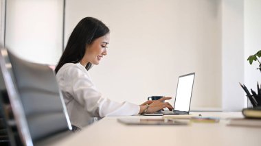 Toplantı odasında dizüstü bilgisayarını kullanan Asyalı genç bir iş kadını ya da kadın ofis çalışanının yan görüntüsü..