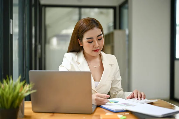 オフィスの彼女の机でビジネスレポートを読み取り 検討白いスーツでフォーカスし プロの千年のアジアの実業家や女性エグゼクティブマネージャー — ストック写真