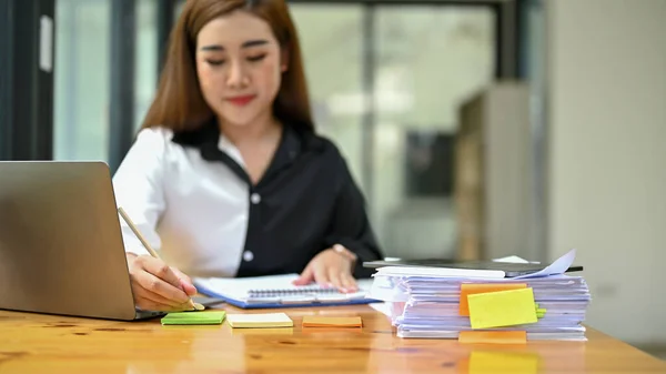 美しい千年のアジアの実業家や女性金融アナリストは 彼女の机で財務報告書を分析しています — ストック写真