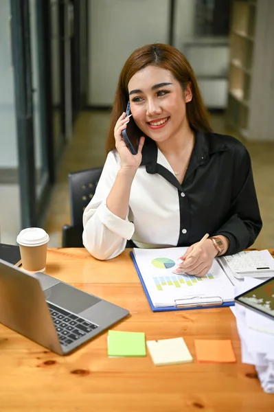 彼女のオフィスで働いている間 魅力的な千年のアジアのビジネスマンは彼女の潜在的なクライアントと電話で話しています — ストック写真