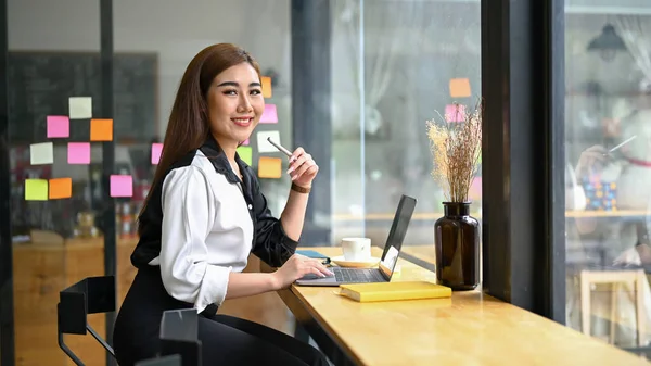 魅力的な千年のアジアのビジネスマンや女性のオフィスワーカーは 彼女のポータブルラップトップでコーヒーショップに座っています — ストック写真