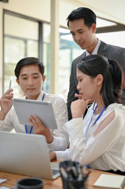 Zeki ve yakışıklı bir Asyalı erkek patron ofiste çalışanlarıyla iş hakkında konuşuyor..