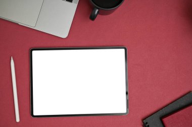 Kırmızı masa üstünde dijital tablet boş ekran modeli, stilus kalem, dizüstü bilgisayar ve kahve fincanı olan modern yaratıcı ofis masası üst görünümü.