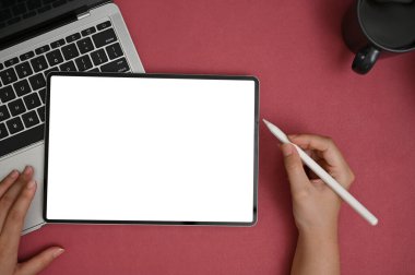 Modern ofis masasında dijital tabletini kullanan bir kadın grafik tasarımcısı. Kırmızı bir masanın üstünde beyaz tablet ekran modeli. en üstteki görünüm