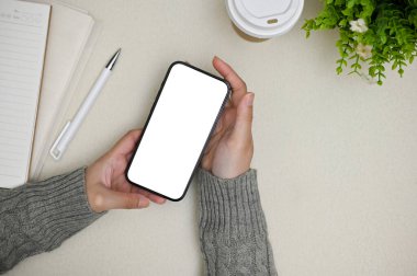 Rahat gri kazaklı bir kadının beyaz bir ekranla minimum gri çalışma masasının üzerinde görüntüsü..