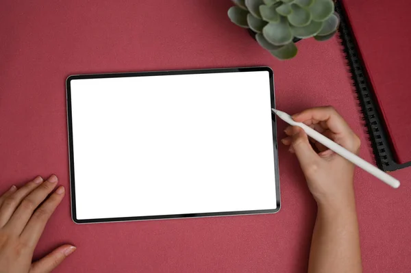 女性の手を保持スタイラスペンのトップビュー 彼女の近代的な赤のオフィスデスクでデジタルタブレット上で描画またはスケッチ タブレットホワイトスクリーンモックアップ — ストック写真