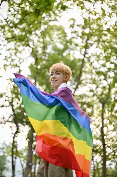 在绿色的公园里 一个年轻迷人的 笑容满面的亚洲男同性恋站在Lgbt彩虹旗的画像 多样性 — 图库照片