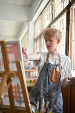 Yaratıcı ve yetenekli genç Asyalı eşcinsel bir adamın portresi sanat eserini yapmaktan, tuval sehpasına akrilik renkler çizmekten ya da stüdyoda akrilik renk atölyesine katılmaktan zevk alır..