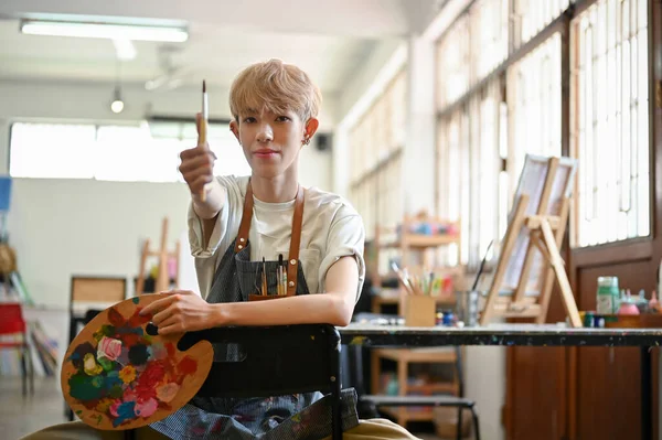 아시아의 재능있는 젊은게이 동성애 예술가가 창의적 스튜디오의 의자에 팔레트를 있습니다 — 스톡 사진