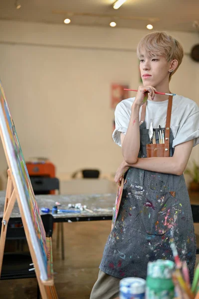 전문적 재능있는 아시아 예술가가 캔버스 이젤에서 자신의 그림을 앞치마를 모습은 — 스톡 사진