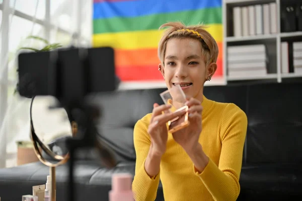 一位快乐的年轻亚洲同性恋选美博主在家中直播时正评论选美产品 — 图库照片