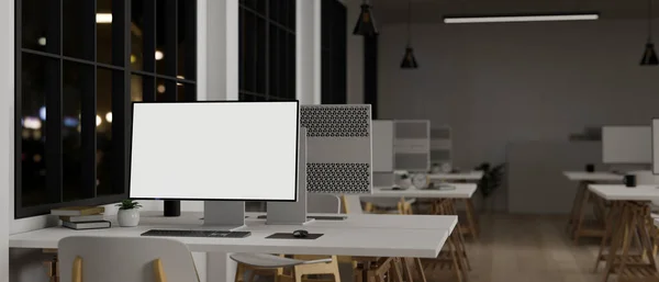 A computer white screen mockup on a white table in a modern office with rows of computers at night. Modern office at night. 3d render, 3d illustration